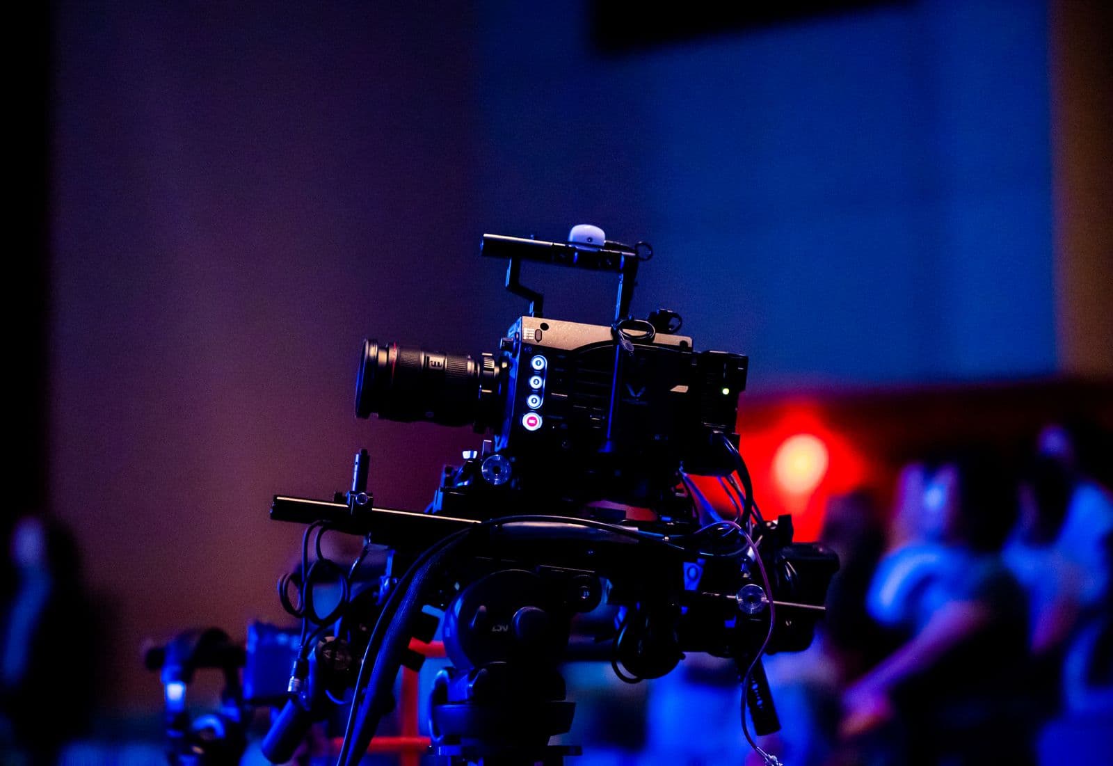 Professional production camera filming a live event under blue stage lighting