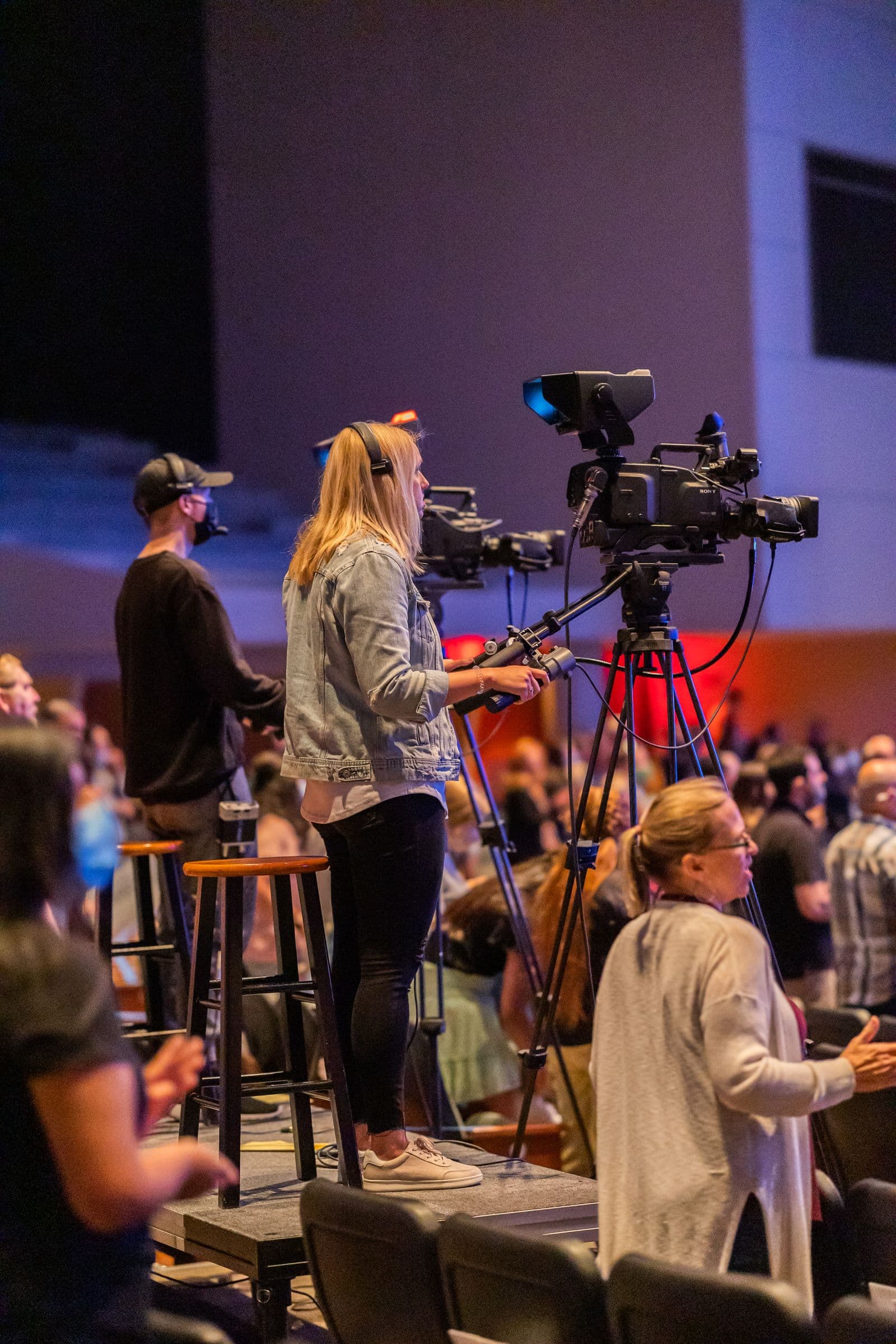 Broadcast camera operators recording a live event from the audience